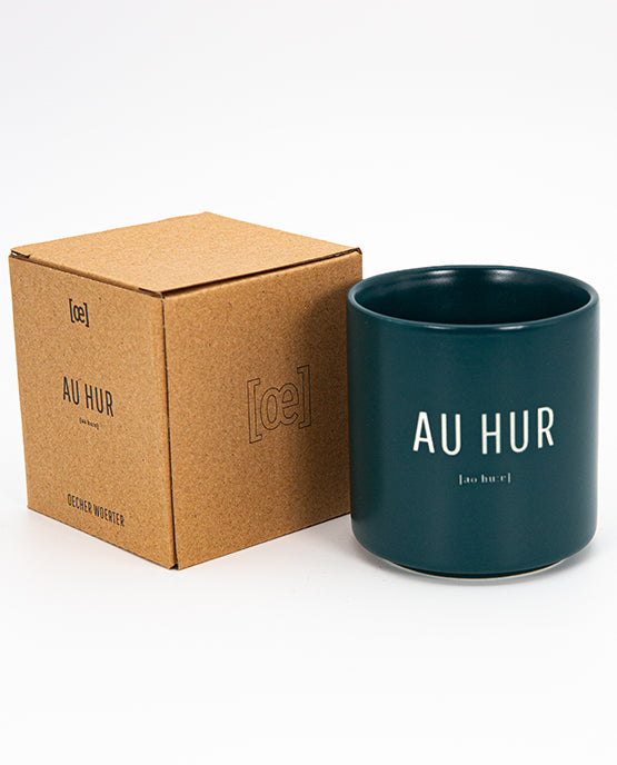 Detailaufnahme eines blauen Keramikbechers mit dem Schriftzug „OECHER JONG“ und phonetischer Lautschrift mit entsprechender Verpackung aus Pappe