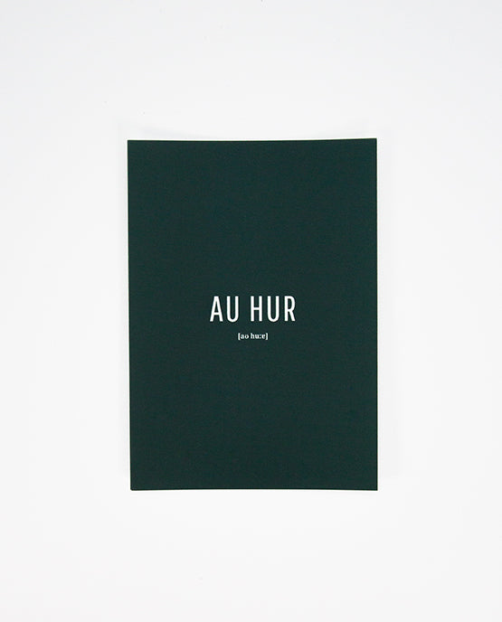 Dunkelgrüne Postkarte mit weißer Aufschrift „AU HUR“ in Großbuchstaben, darunter in kleiner Schrift die phonetische Schreibweise „[ao huːr]“.