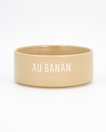 Beige Keramischale mit weißem Schriftzug „AU BANAN“ vor weißem Hintergrund 