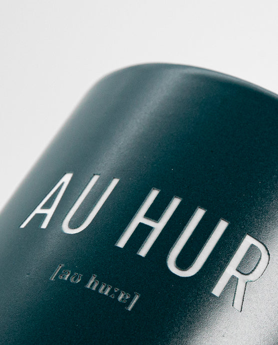 Detailaufnahme eines petrolfarbenen Keramikbechers mit dem Schriftzug „AU HUR“ und phonetischer Lautschrift
