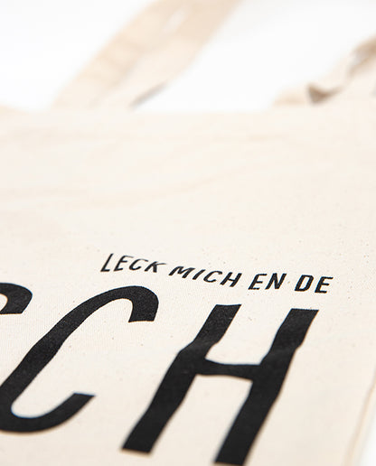 Detailaufnahme des naturfarbenen Jutebeutels mit schwarzem Druck „LECK MICH EN DE TÄSCH“ 