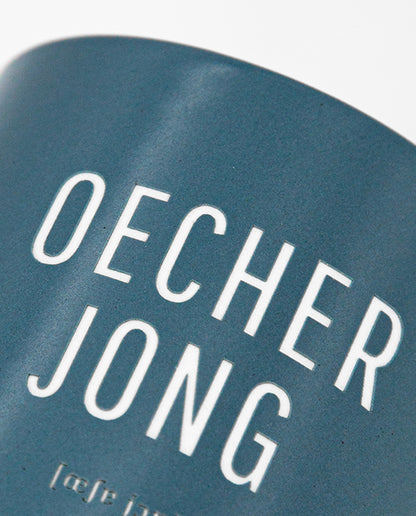 Detailaufnahme eines blauen Keramikbechers mit dem Schriftzug „OECHER JONG“ und phonetischer Lautschrift