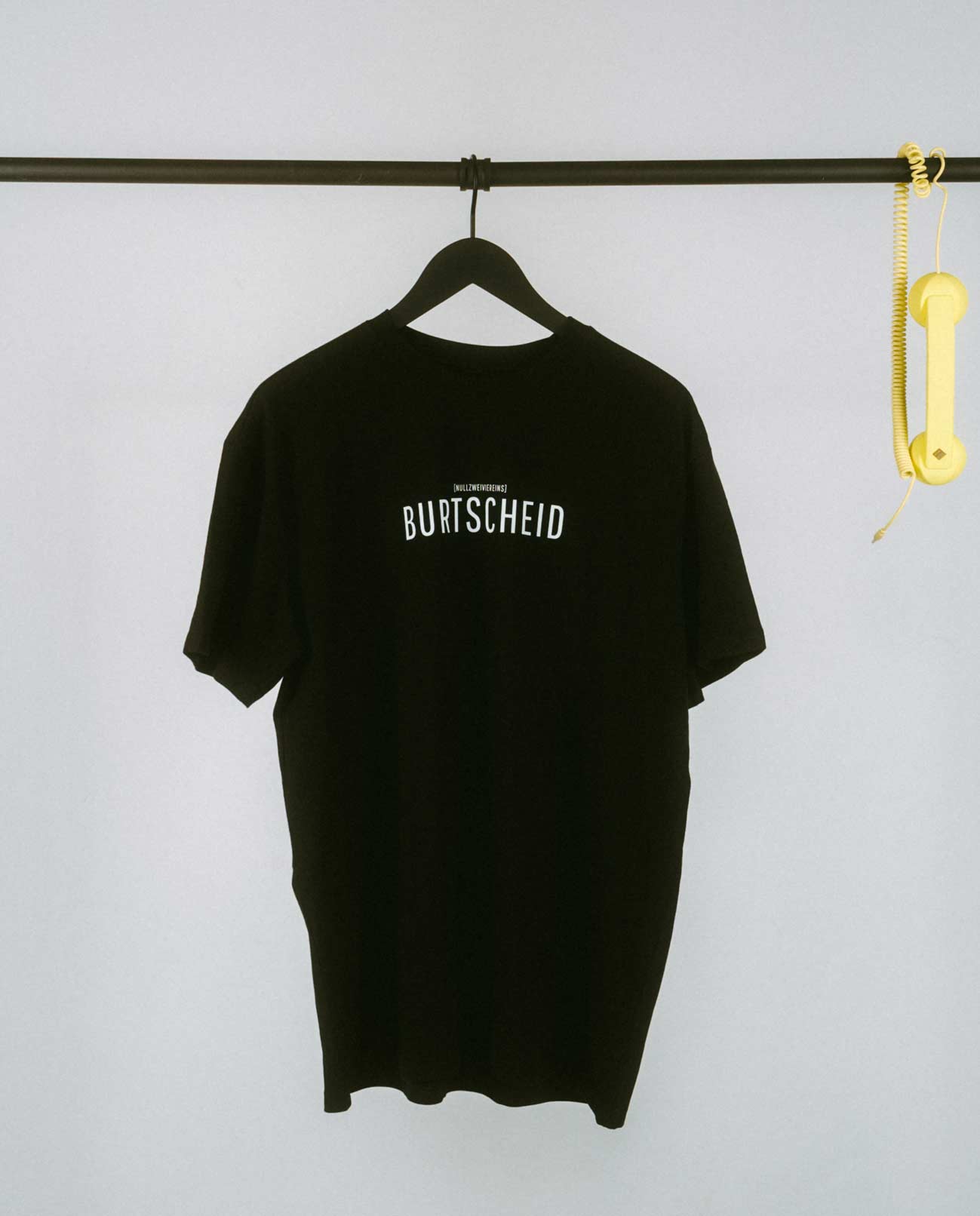 Schwarzes T-Shirt mit zentral platziertem Schriftzug „BURTSCHEID“ in klaren, schwarzen Großbuchstaben. Oberhalb des Namens ist dezent [NULLZWEIVIEREINS] angebracht, als Hinweis auf die Aachener Vorwahl. Ein cleanes, zeitloses Design für alle, die ihren Stadtteil stilvoll präsentieren möchten.