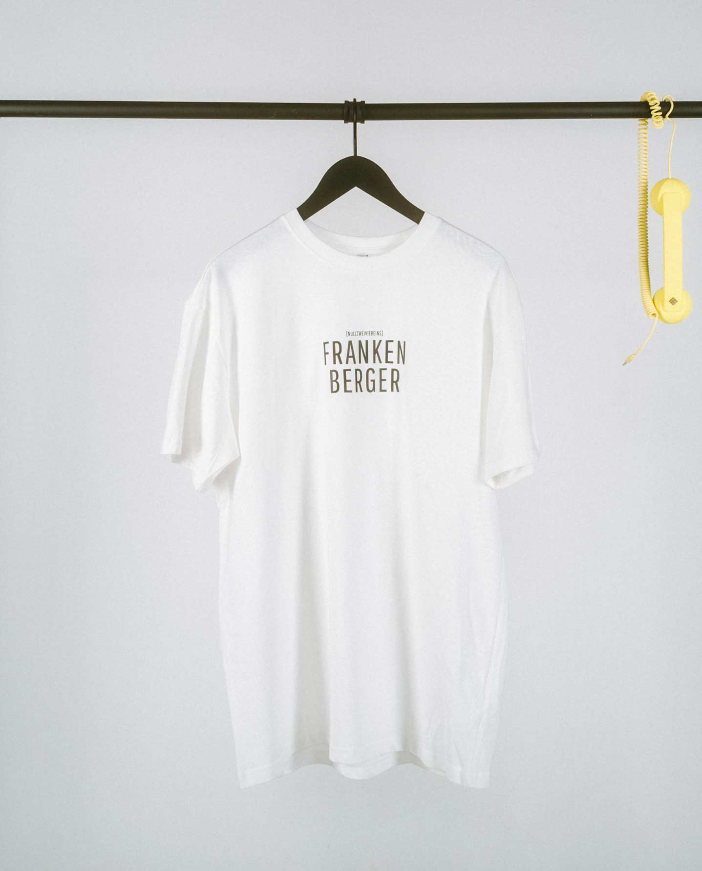 Weißes T-Shirt mit schwarzem Aufdruck „FRANKENBERGER“ in Großbuchstaben, mittig auf der Brust platziert.